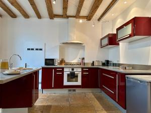 a kitchen with red cabinets and a stove top oven at Maison cosy à côté de Beaune in Savigny-lès-Beaune