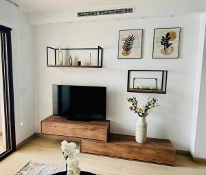 un salon avec une télévision et un vase fleuri dans l'établissement Apartament z Basenem i Jacuzzi Benidorm Finestrat, à Finestrat