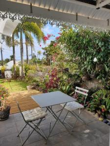 a table and two chairs on a patio with flowers at Ô Ravenale Manapany Les Bains in Saint-Joseph
