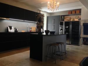 a kitchen with black cabinets and two bar stools at PROVENCEguesthouse L'Agace in Forcalquier