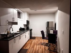 a kitchen with black counter tops and a refrigerator at Homey Basement Suite by Gaudi in Calgary