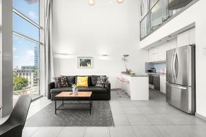 a living room with a black couch and a kitchen at Mr Neve Tsedek in Tel Aviv