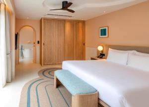 a bedroom with a large white bed and a blue bench at Centara Karon Villas Phuket in Karon Beach