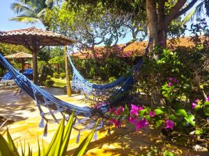 a couple of hammocks in a garden with flowers at Villa Maree in Pipa