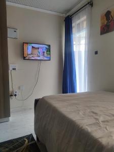 Kitengela にあるB&G staycationのベッドと壁にテレビが掛かった寝室 +1枚の写真