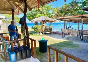 a man sitting on a bench next to the beach at Enas Cottage Pamilacan IsLand in Baclayon