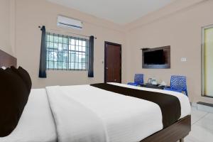 a bedroom with a large white bed and blue chairs at Super Collection O Chikmagalur Zilla Panchayat Formerly Relax Inn in Chikmagalūr +23 photos