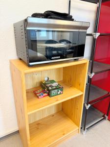 a microwave oven sitting on a wooden shelf at Berta - Zentrale Wohnung - 2 Küchenzeilen - Nähe Bahnhof in Schwerin