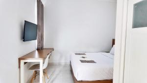 une chambre avec un lit, un bureau et une télévision dans l'établissement Damar Kusumo Exclusive Guest House, à Seturan