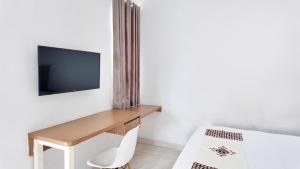 une pièce avec un bureau et une télévision sur un mur dans l'établissement Damar Kusumo Exclusive Guest House, à Seturan