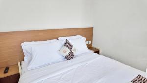 - un lit avec des draps blancs et 2 oreillers dans l'établissement Damar Kusumo Exclusive Guest House, à Seturan