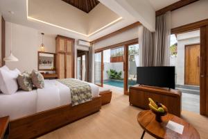 a bedroom with a bed and a television and a table at La Tropica Canggu Bali By Kanaya Hospitality in Canggu