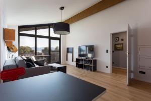 Una sala de estar con un sofá y un televisor. en Designer-Oberstüberl mit Seeblick auf den Chiemsee & Alpenpanorama, en Seebruck