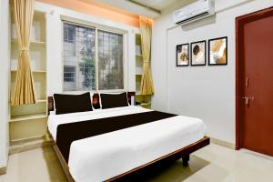 a bedroom with a large white bed in front of a window at Super Collection O Balewadi formerly Woods Regency in Pune +24 photos
