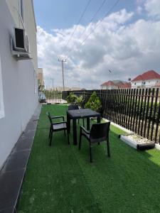 a patio with a table and chairs on the grass at Luxury Smart 3-Bedroom Semi-Detached Apartment in Abuja