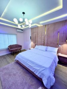 a bedroom with a large white bed and a couch at Luxury Smart 3-Bedroom Semi-Detached Apartment in Abuja