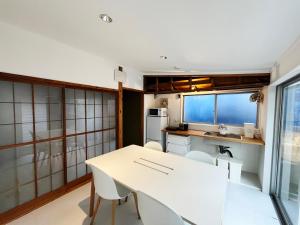 a small kitchen with a white table and chairs at Guest House NOMAYADO in Shizuoka