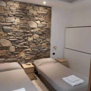 zwei Betten in einem Zimmer mit einer Steinwand in der Unterkunft B&B linate in Peschiera Borromeo