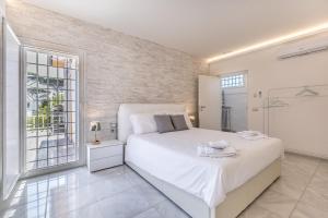 a bedroom with a white bed and a brick wall at Relais Roma Beach in Fregene +43 photos