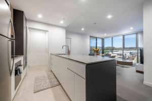 een keuken met witte en zwarte apparatuur en een woonkamer bij Chic 2 Bedroom Escape with Premium Amenities in Phillip