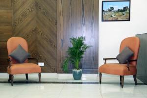 two orange chairs and a potted plant in a room at Amchit Grand Hotel in Al Qarfī