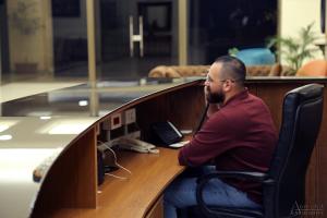 a man sitting at a desk talking on a phone at Amchit Grand Hotel in Al Qarfī