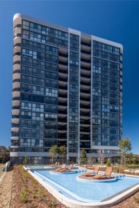 een gebouw met een zwembad en ligstoelen ervoor bij Chic 2 Bedroom Escape with Premium Amenities in Phillip