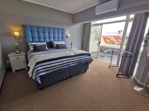 a bedroom with a large blue bed and a balcony at Port Owen Marina by First Private Stays in Velddrif