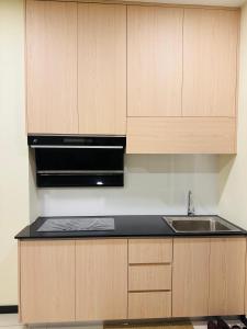 a kitchen with wooden cabinets and a sink at City Apartment next to The Spring in Bintulu