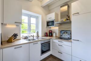 a kitchen with white cabinets and a sink at Haus Wind&Wellen, Wohnung Hafen in Wittdün
