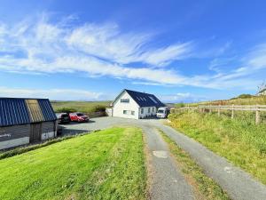 a dirt road leading to a white house with a barn at Clouds B&B in Kilmuir
