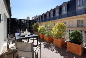 uma varanda com mesa, cadeiras e vasos de plantas em Eurostars Casa de la Lírica em Madri