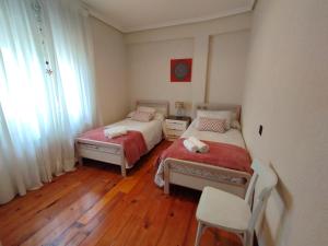 a bedroom with two beds and a chair and a window at Apartamento La Luz de Reinosa 2 in Reinosa