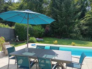 a table with an umbrella next to a pool at Chez Jo in Le Valdahon