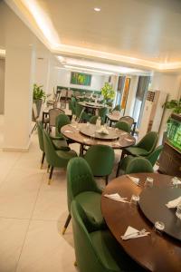 a restaurant with wooden tables and green chairs at AXIL HÔTEL in Dakar