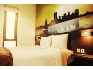 - une chambre dotée d'un lit blanc et d'une fresque murale représentant la ville dans l'établissement Pondok Labu Residence, à Jakarta