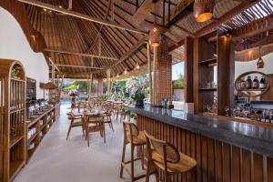 a restaurant with a bar and tables and chairs at La Tropica Canggu Bali By Kanaya Hospitality in Canggu
