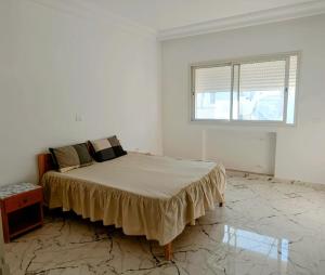 a white bedroom with a bed and a window at Appartement a Hammamet Lux in Hammamet