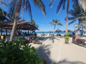 a beach with palm trees and people on the beach at Khách sạn Monaco Đà Nẵng in Da Nang