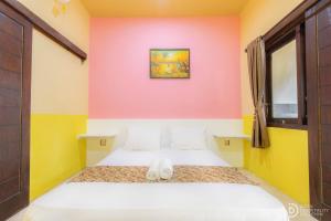 Brown Sugar Homestay في غيلي تراوانغان: غرفة نوم بسرير وجدران صفراء وردية