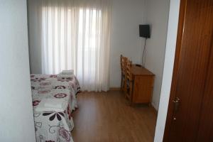 Hostal La Tablada في نافالينو: غرفة نوم بسريرين وخزانة ونافذة
