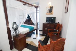 ein Schlafzimmer mit einem Bett, einem Schreibtisch und einem Fernseher in der Unterkunft Cinnamon Crest Resort & Ayurveda Spa in Kandy
