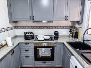 La cuisine est équipée de placards gris et d'un four avec plaques de cuisson. dans l'établissement SunRise Den, a pie de playa, vista al mar y piscina, à El Alamillo