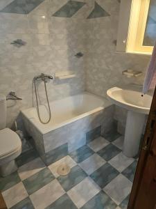 a bathroom with a tub and a toilet and a sink at Country Home in Áyios Spirídhon