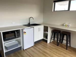 a kitchen with a sink and a counter with stools at Stylish Space in Twizel +3 photos