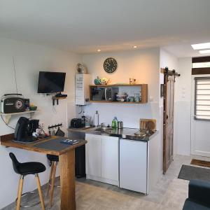 a kitchen with white cabinets and a table and a desk at Studio L'audrerie. in Saint-Pardoux-Corbier