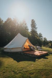 a tent with two chairs and a table in a field at Glamping Natur Resort Jetřichovice in Jetřichovice