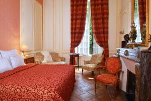 Hôtel d'Argouges في بايو: غرفة نوم بسرير احمر وكراسي ونافذة