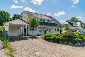 ein großes weißes Haus mit einer Ziegelsteinfahrt in der Unterkunft Ferienhaus "Stella Olivia" in Lobbe