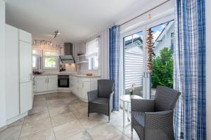 eine Küche mit weißen Schränken und einem Tisch und Stühlen in der Unterkunft Ferienhaus "Stella Olivia" in Lobbe